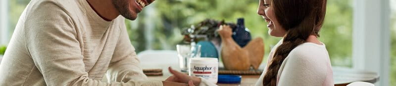 man applying Aquaphor Healing Ointment on daughter's hands