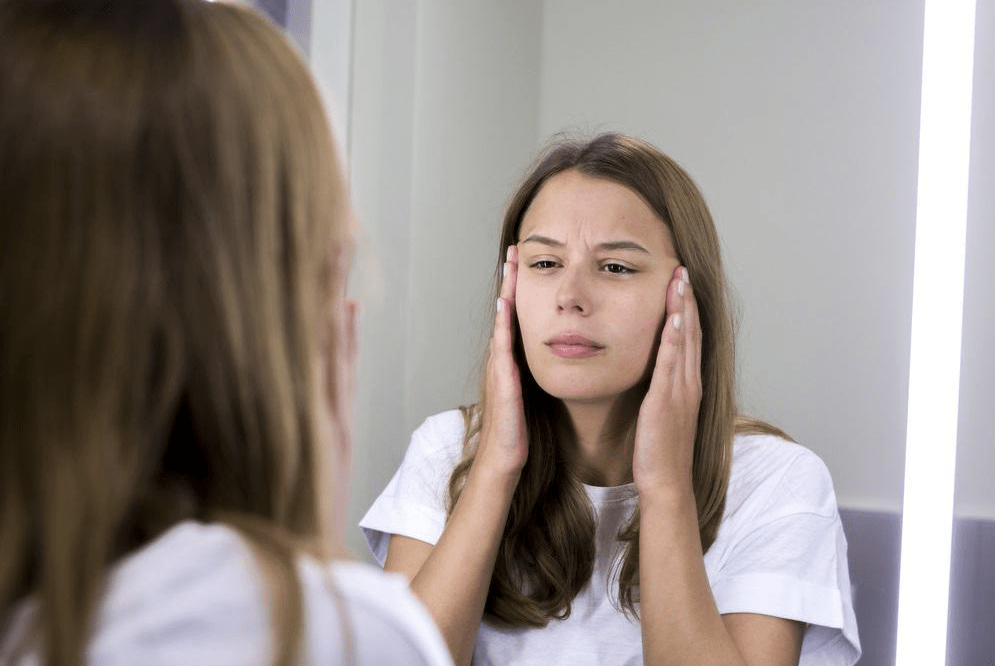 Woman looking at skin in mirror
