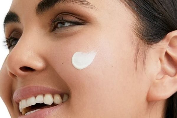 Frau lacht und hat Creme auf der Wange.