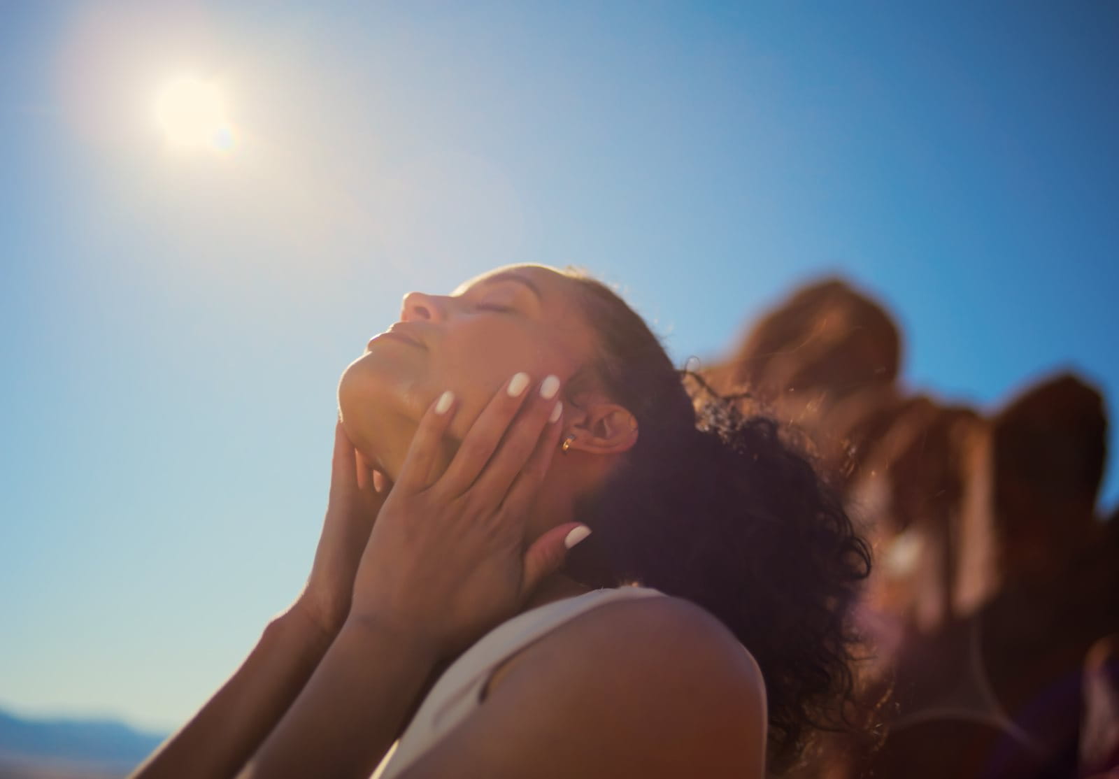 Woman standing in the sun with her hands on her face