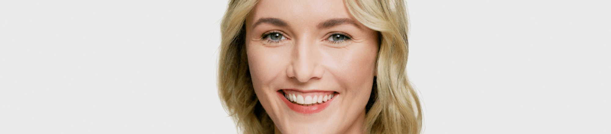 Blonde woman smiling on a grey background