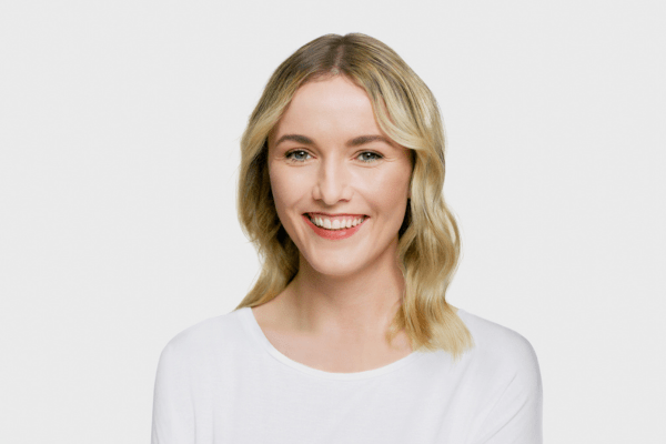 Blonde woman smiling on a grey background
