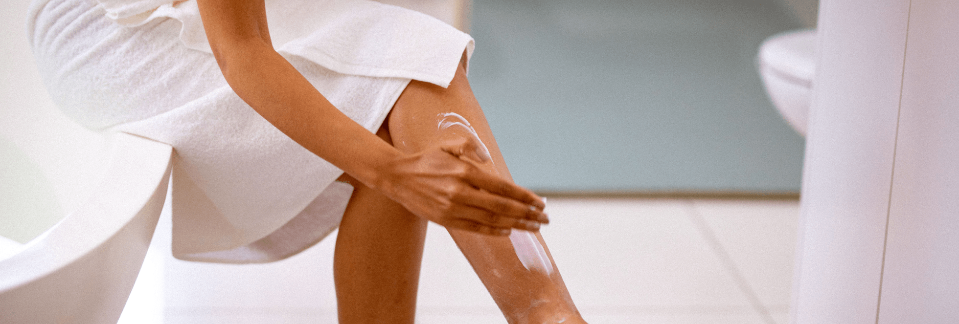 A women applying moisturiser to itchy legs after a shower