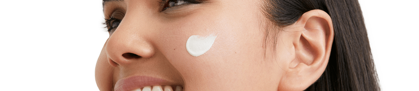 Woman smiling with face cream on her cheek