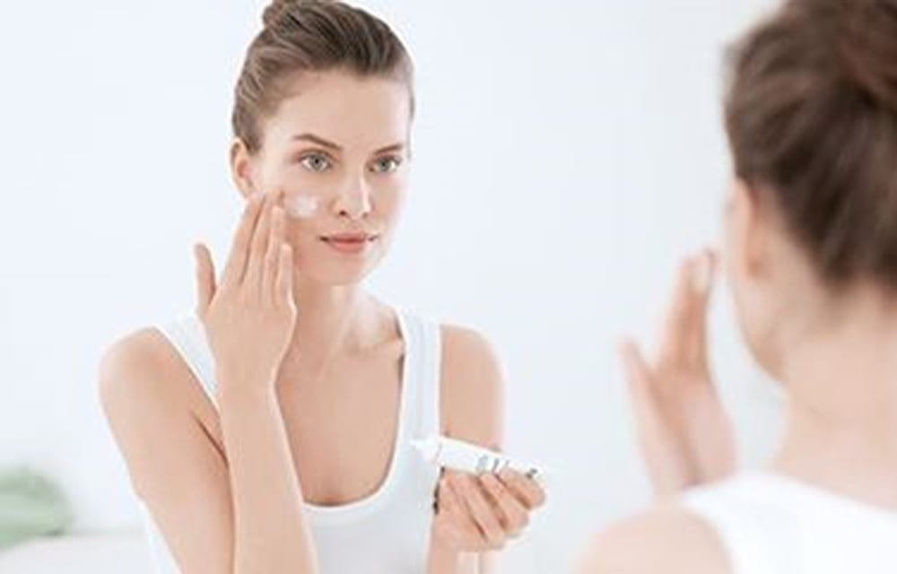A woman applying DermoPurifyer Oil Control Mattifying Fluid as a moisturiser on acne prone skin - Eucerin