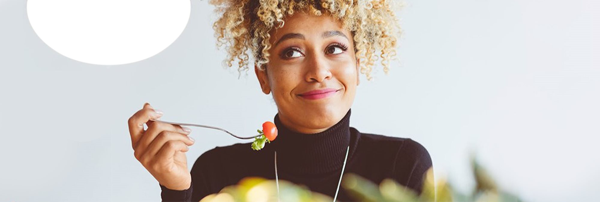 A woman eating a cherry tomato to fight acne - Eucerin