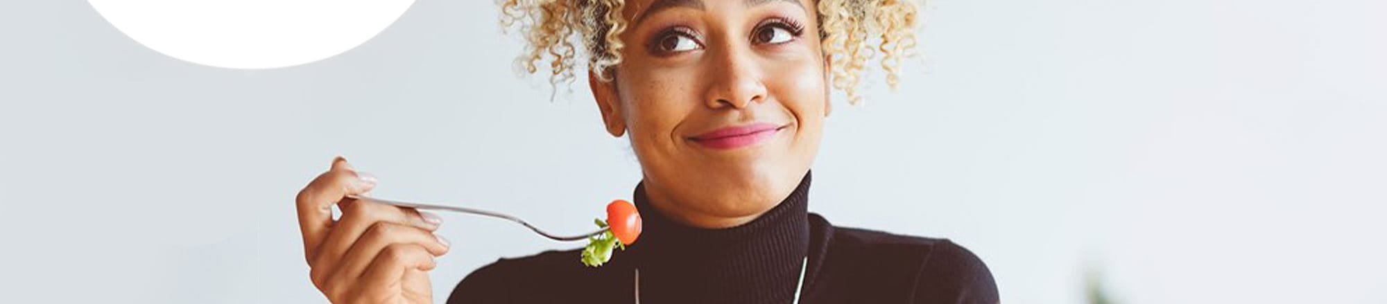 A woman eating a cherry tomato to fight acne - Eucerin