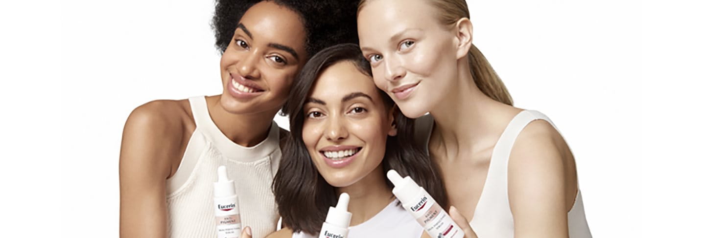 Tre kvinnor som håller Anti-Pigment Skin Perfecting serum som ger lyster och glow