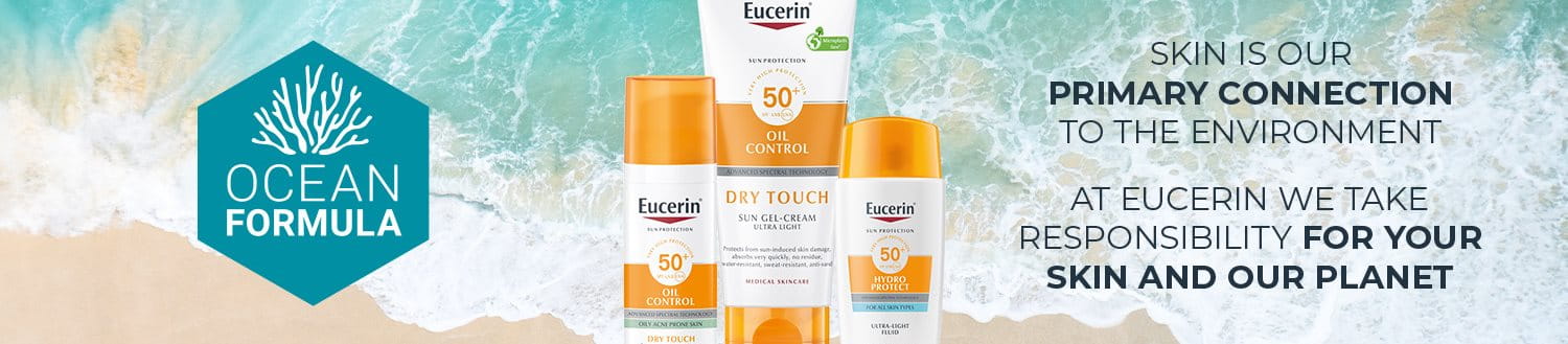 Een selectie van Eucerin zonneproducten op een zandstrand voor een golf