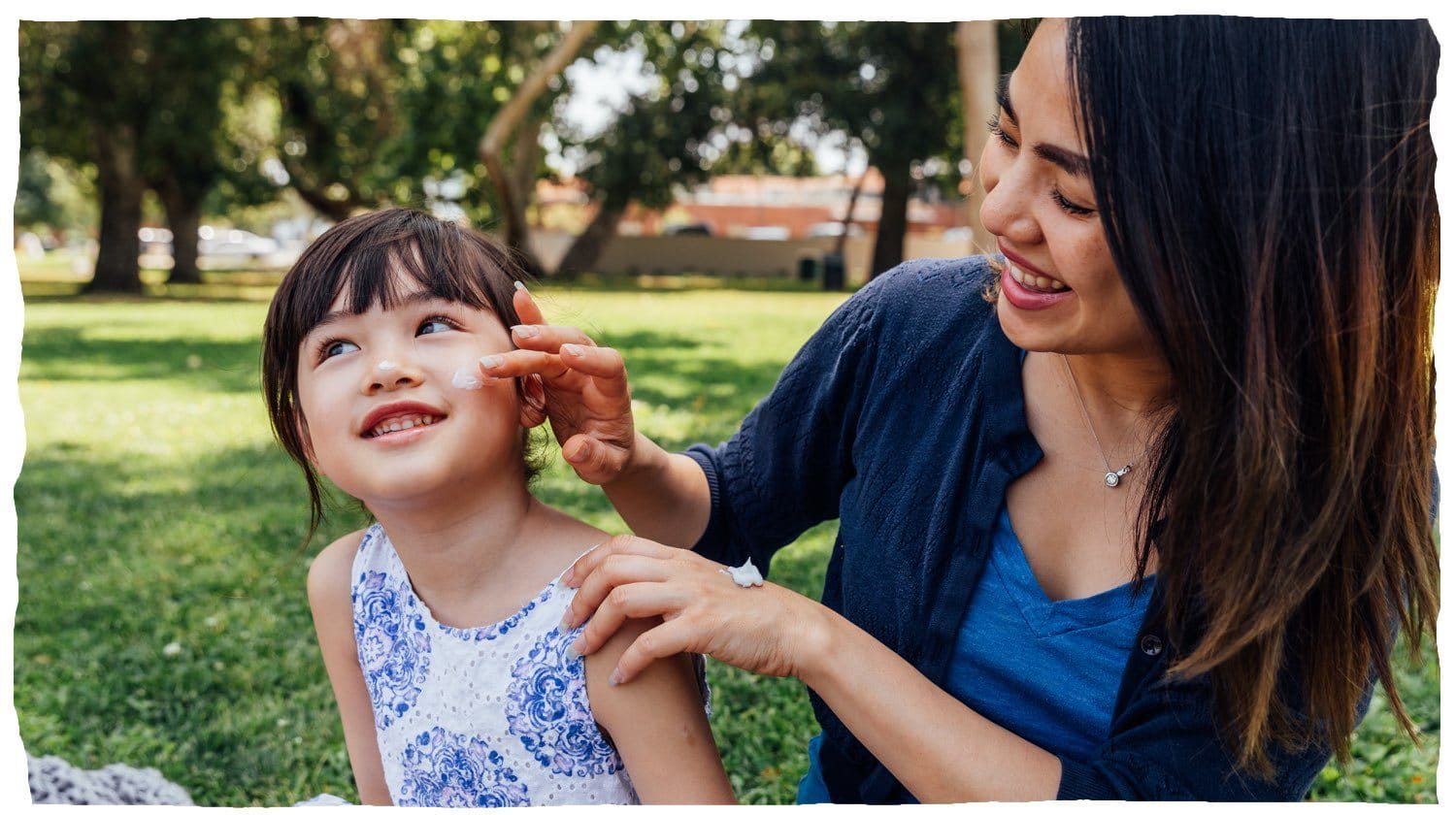 Une femme appliquant une lotion sur la joue d’un enfant.