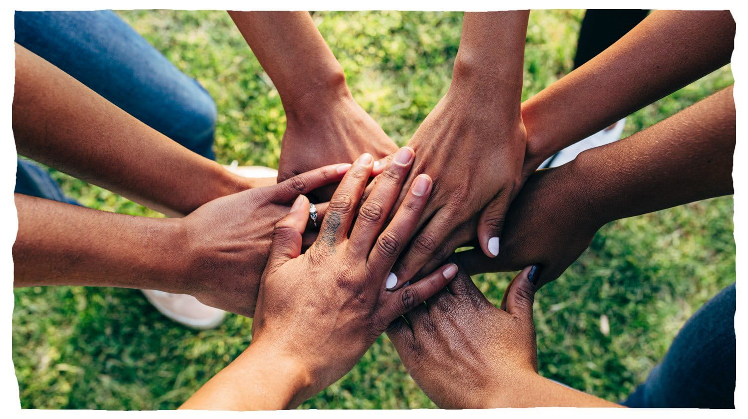 People putting their hands together in a circle, representing teamwork. 