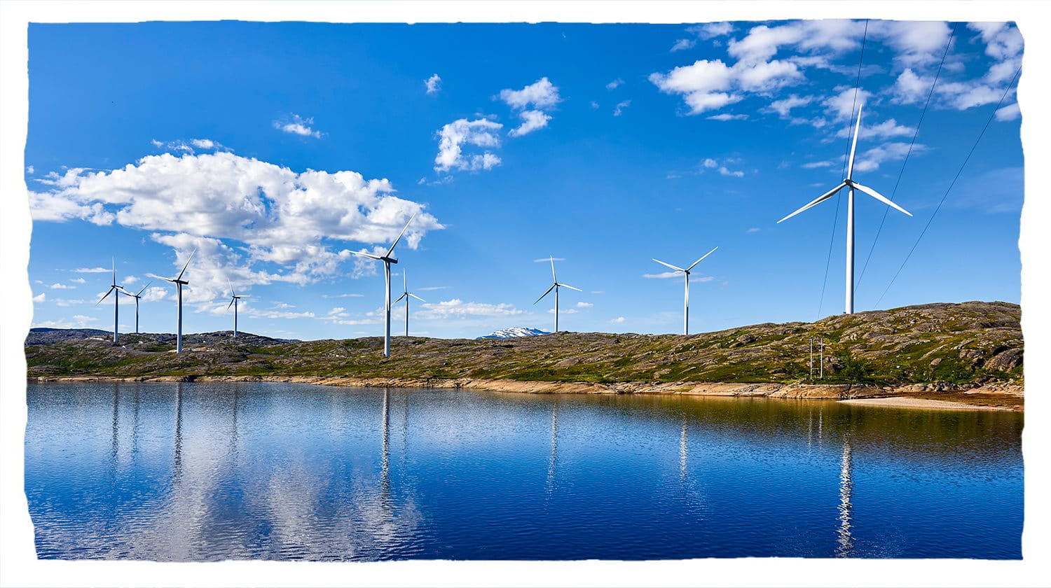 Wind turbines visible on the hills alongside a lake.