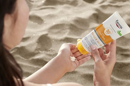 Persona aplicando protección solar para cara y cuerpo