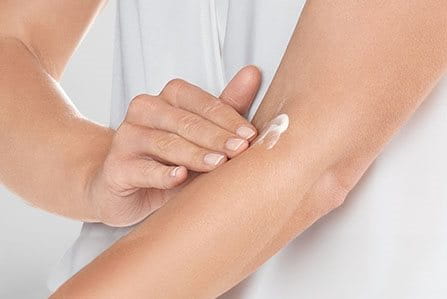 Una científica se aplica la crema en el dorso de la mano y un científico la observa.