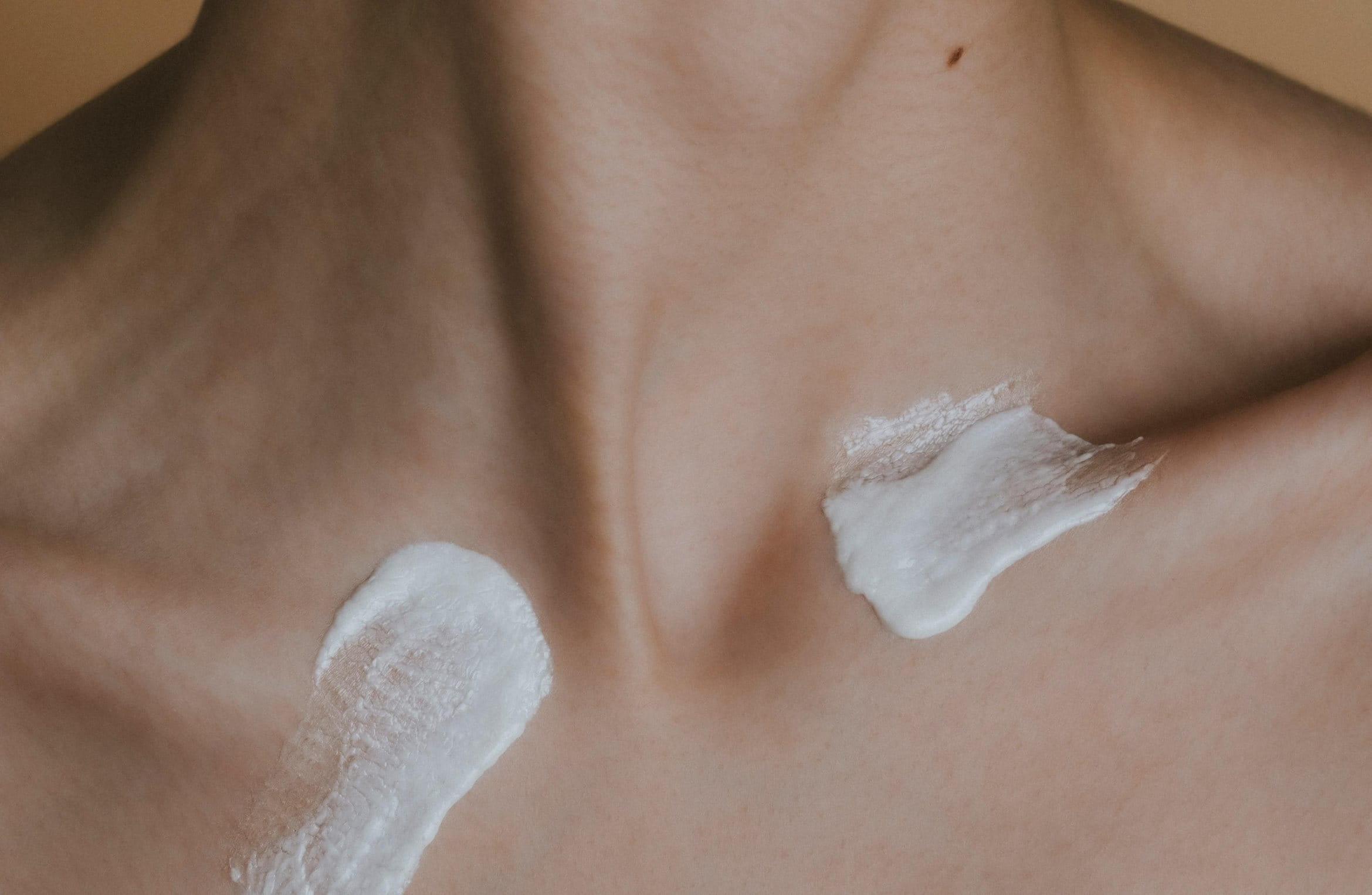 Frau mit Creme am Hals dreht ihren Kopf zur Seite.