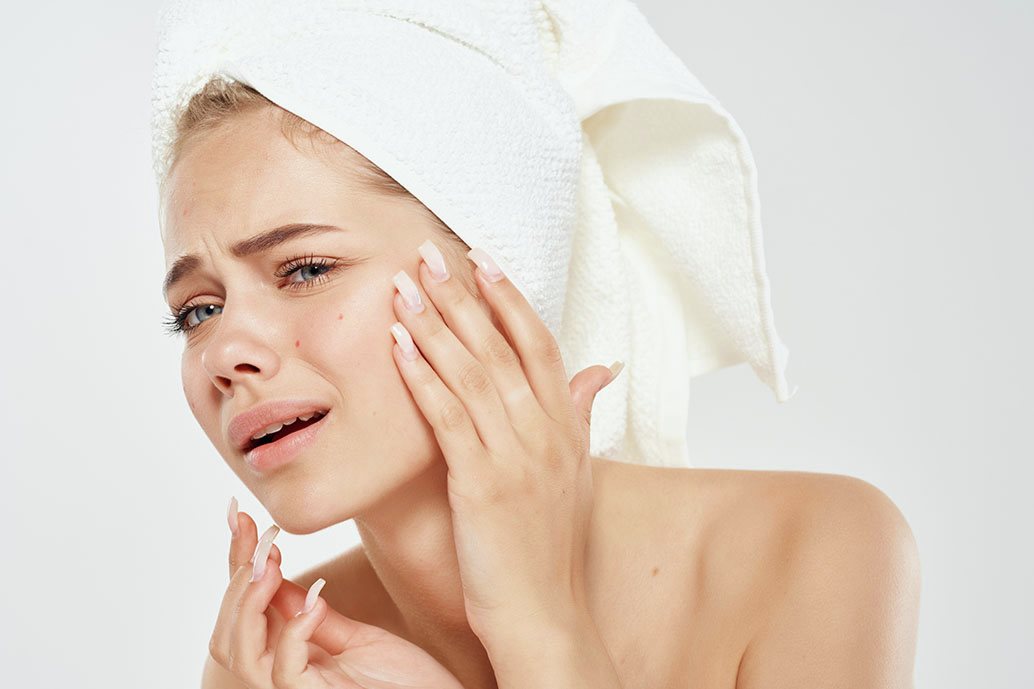 Persona con asciugamano in testa osserva la pelle del viso da vicino, preoccupata per inefficacia skincare
