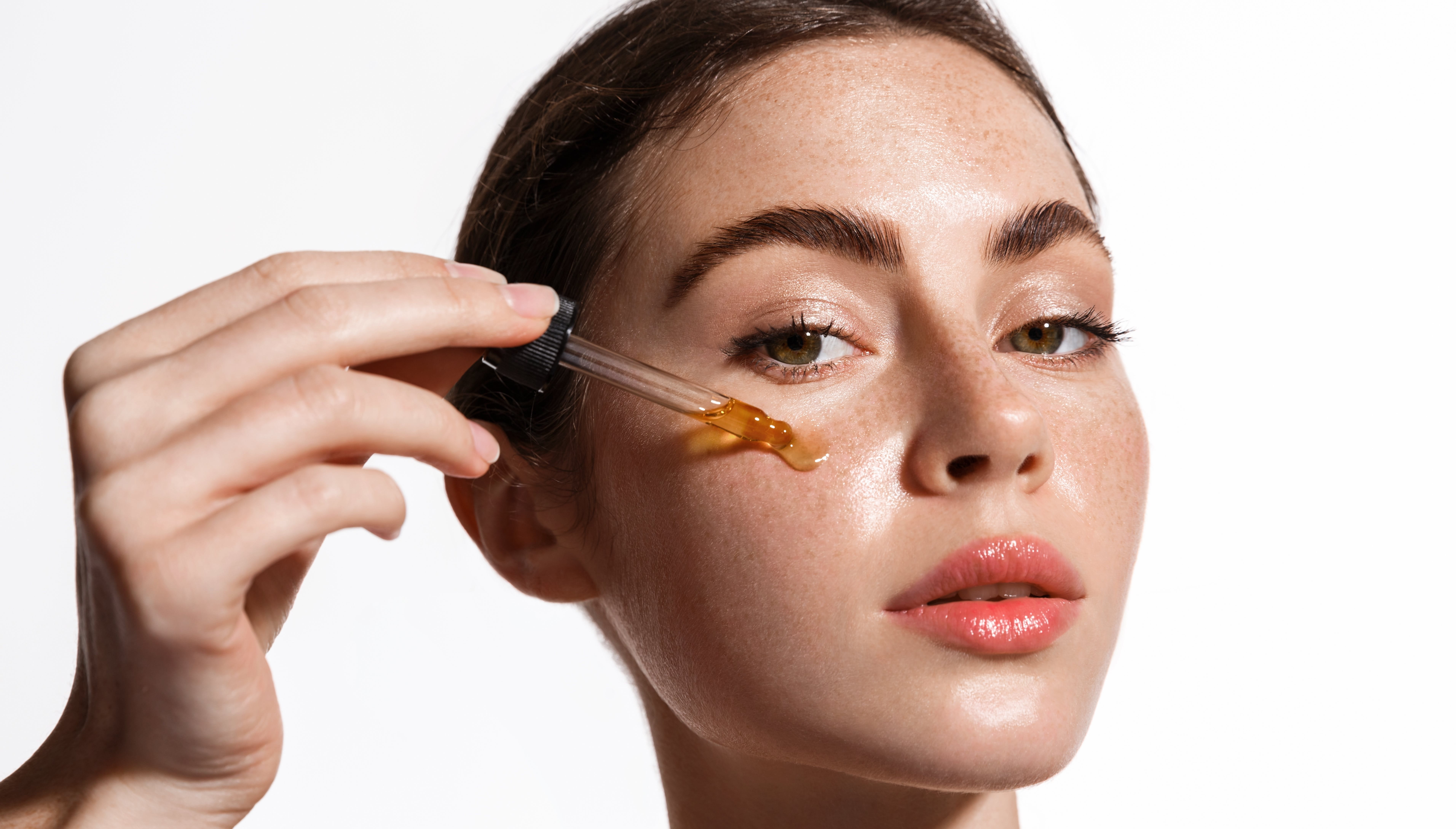Femme appliquant un sérum visage à l'aide d'une pipette sur sa peau.
