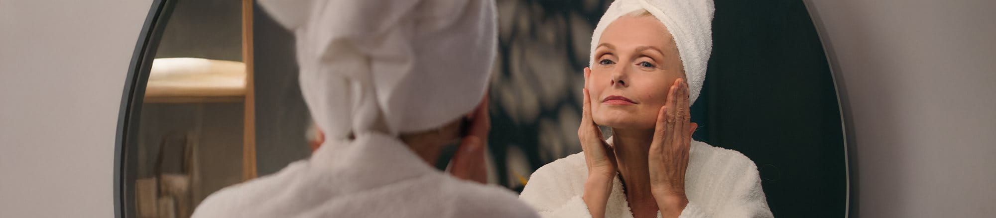 Frau betrachtet sich im Spiegel