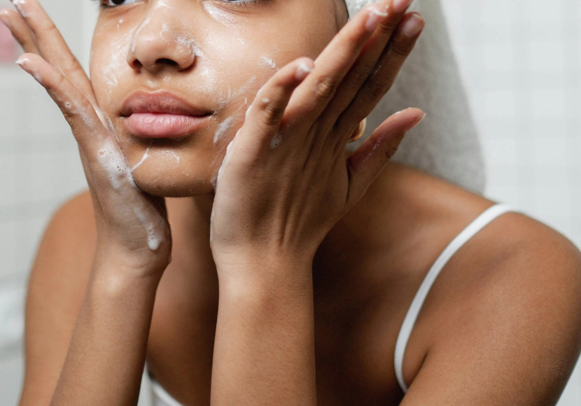 Mädchen reinigt Gesicht mit beiden Händen.