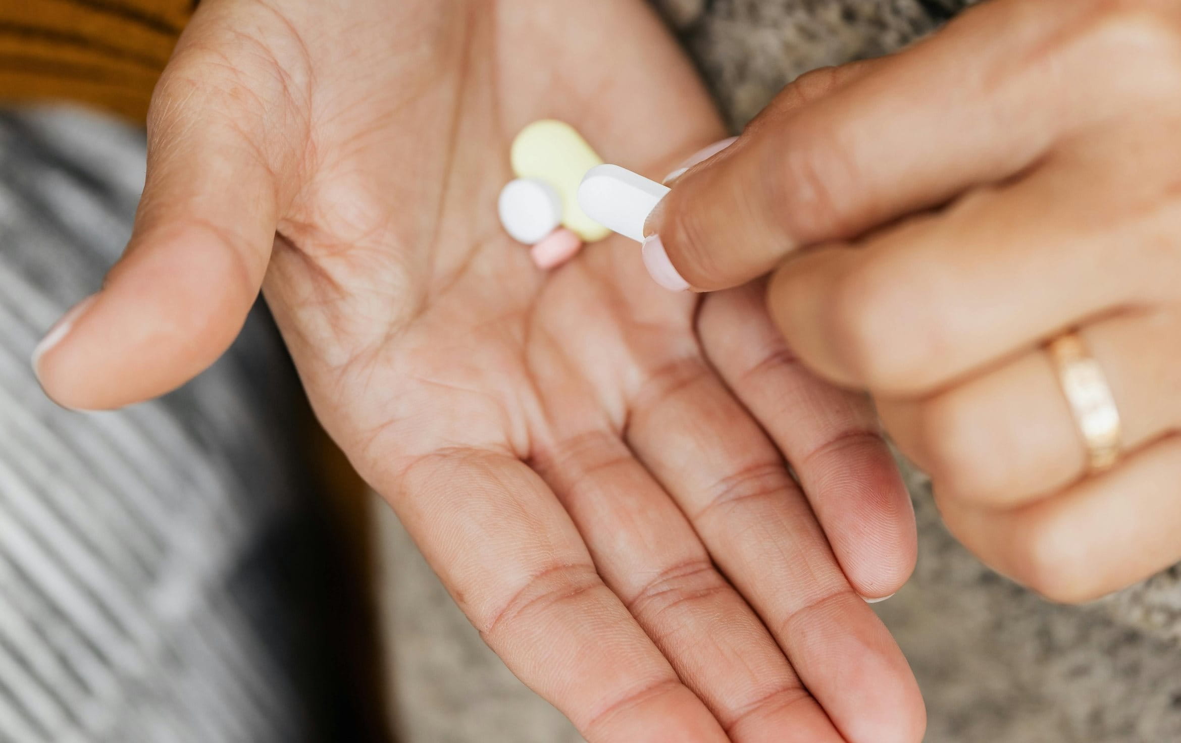 Frau hat mehrere Tabletten in ihrer Handfläche. Eine Tablette hält sie mit den Fingern.