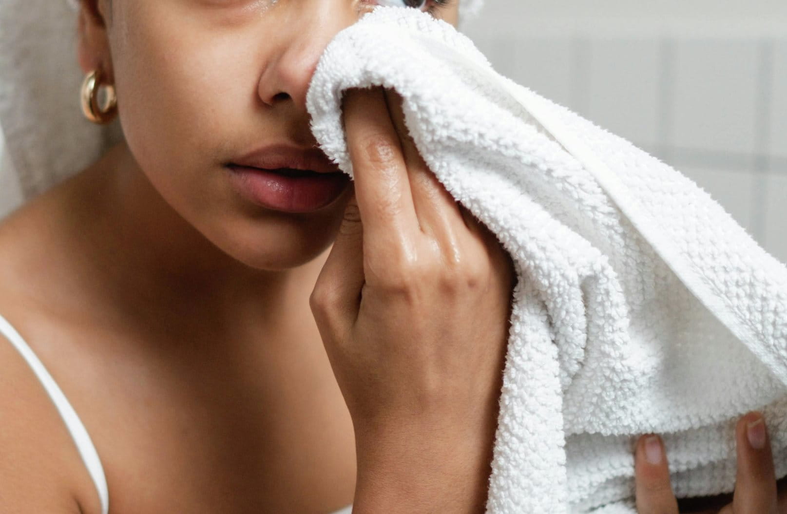 Frau klärt Gesicht mit einem weissen Handtuch.