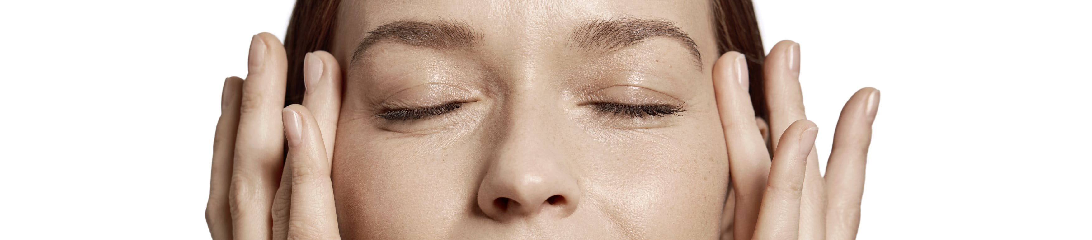 nainen koskettaa kasvojaan
