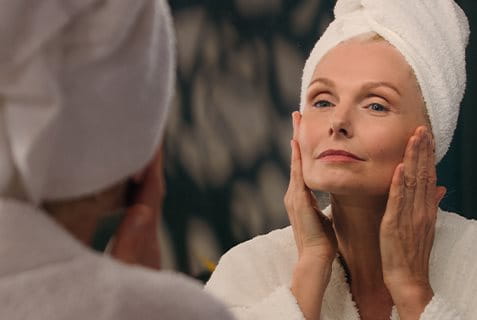 Frau betrachtet Gesicht im Spiegel