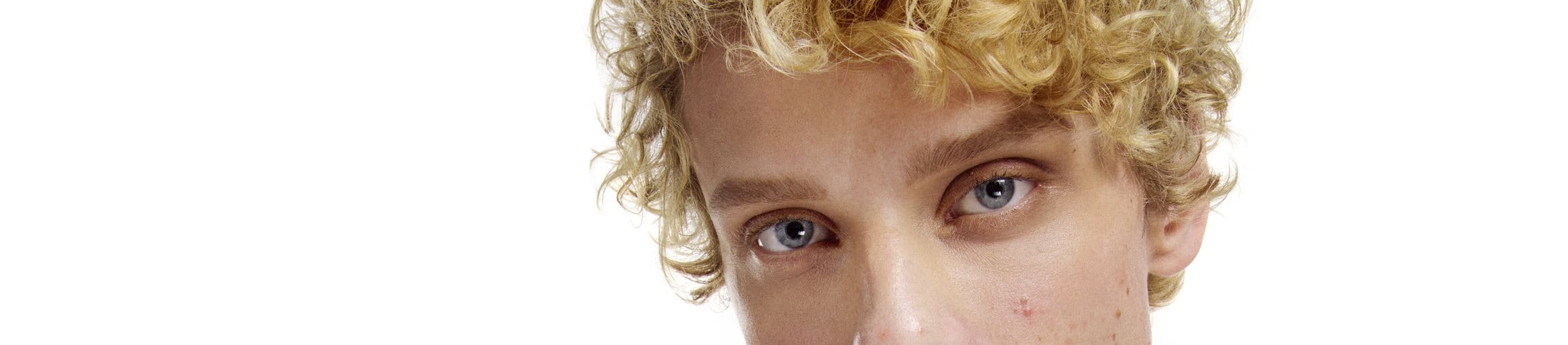 bild av en blond pojke som tittar in i kameran mot en vit bakgrund