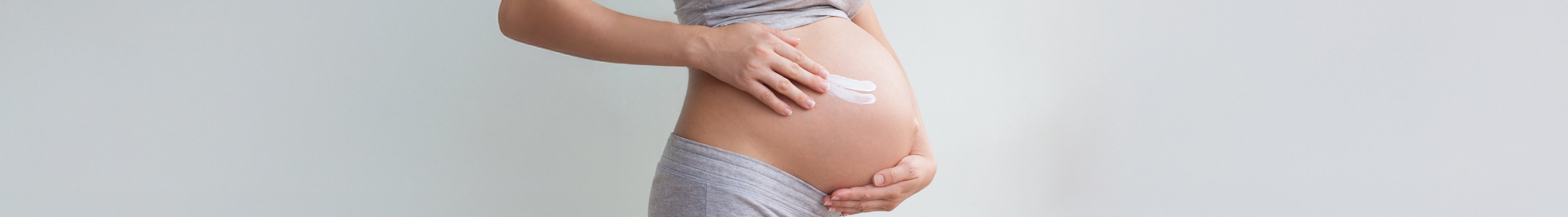 Schwangere Frau mit Creme am Bauch