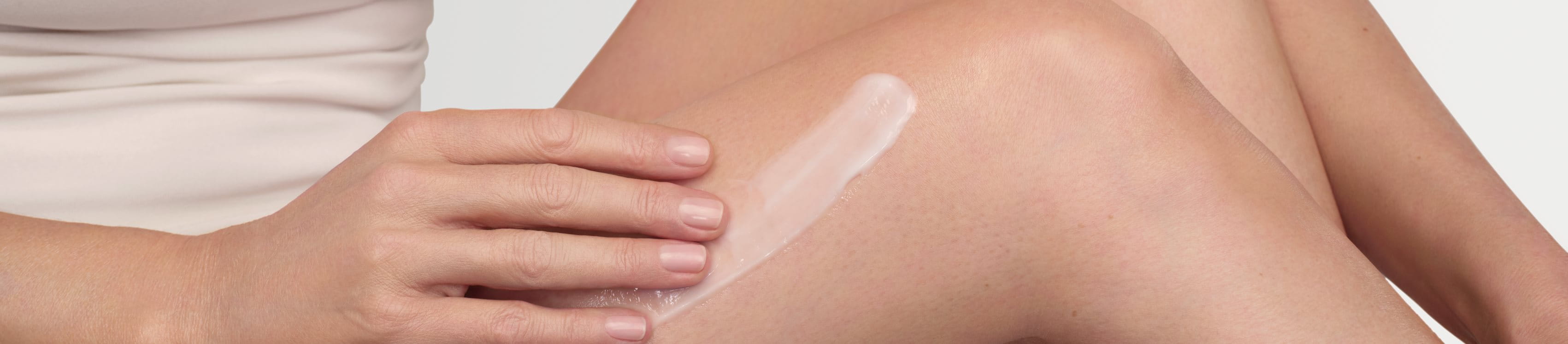 A woman applying lotion to her legs