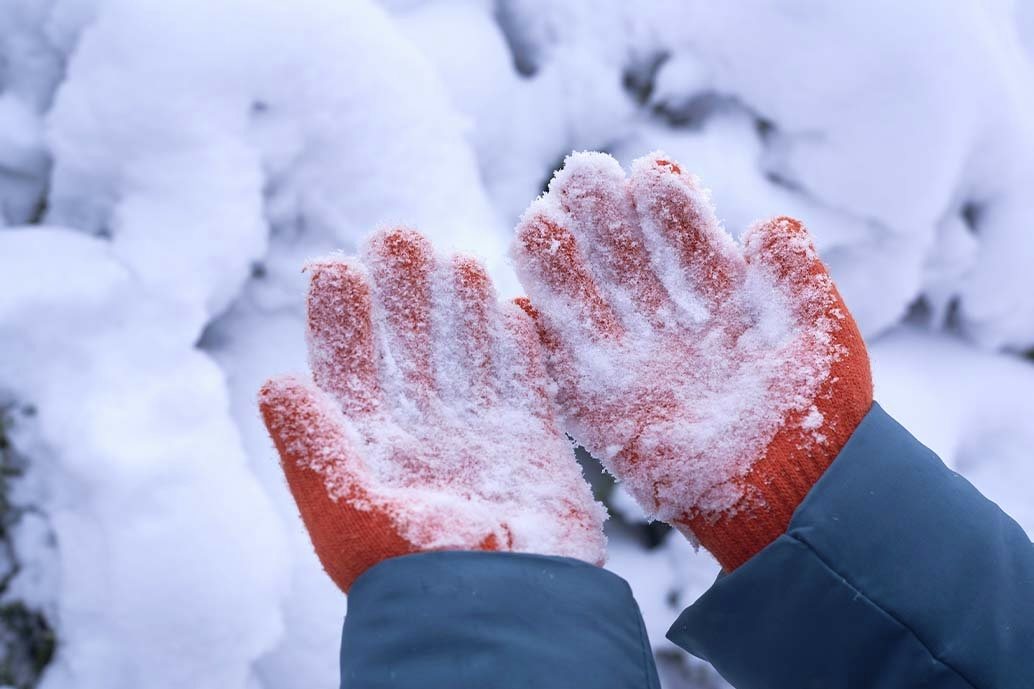 mani con guanti che toccano la neve