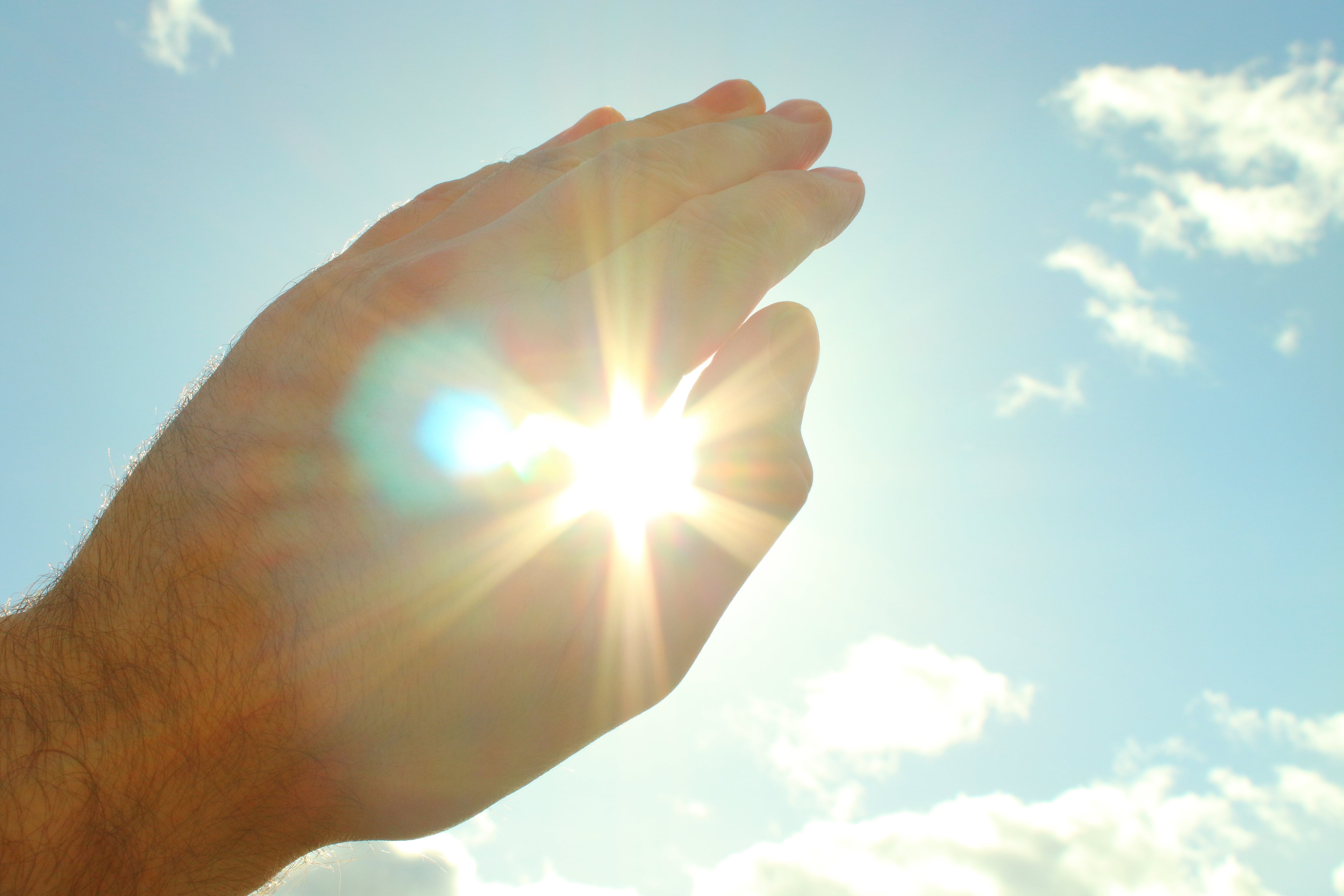 Nahaufnahme der Hand einer Person, die die Sonne abschirmt