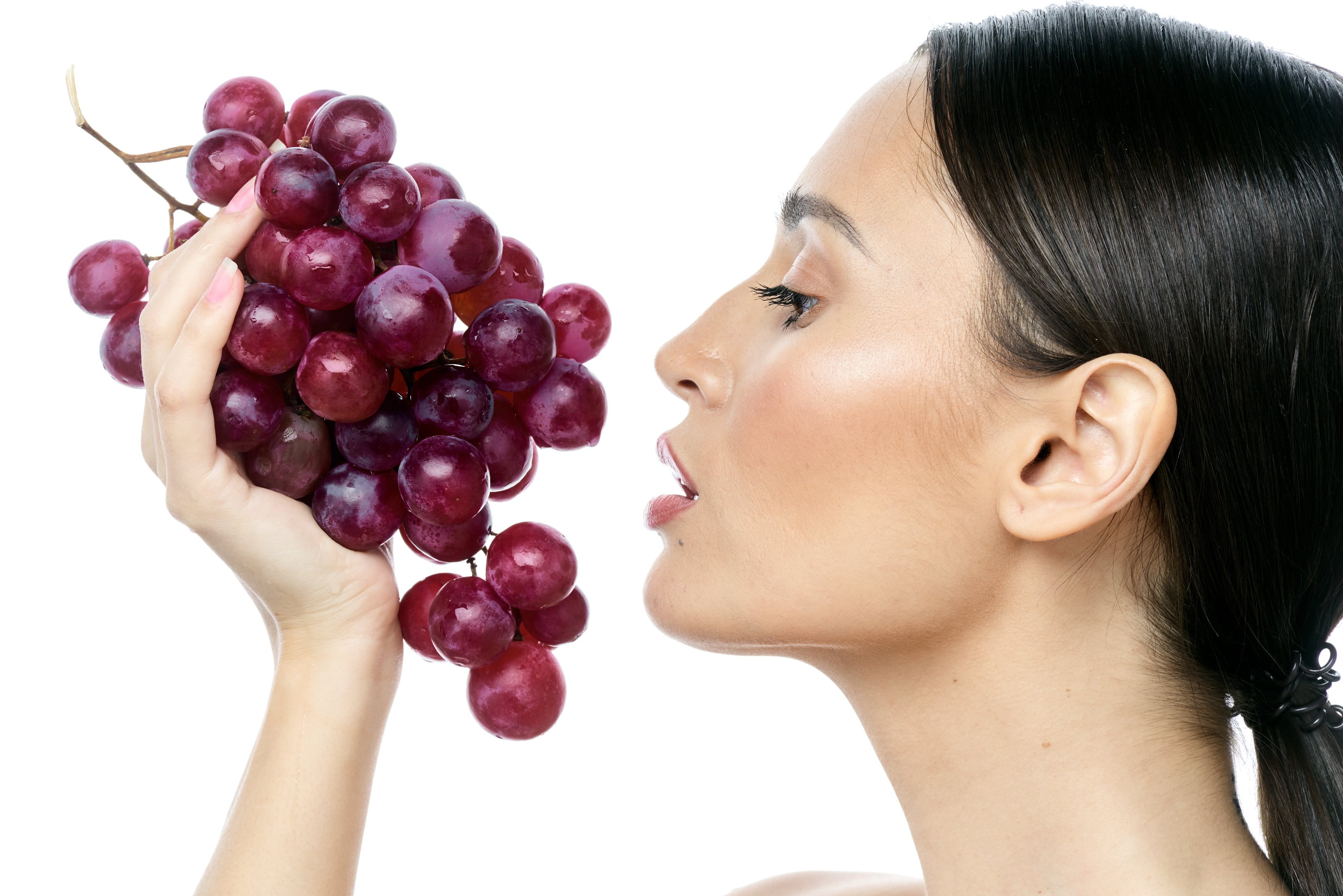 Profilansicht einer Frau, die eine Traubenrebe in der Hand hält.
