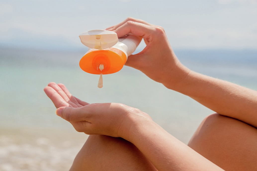 ragazza che utilizza crema solare per proteggere la pelle