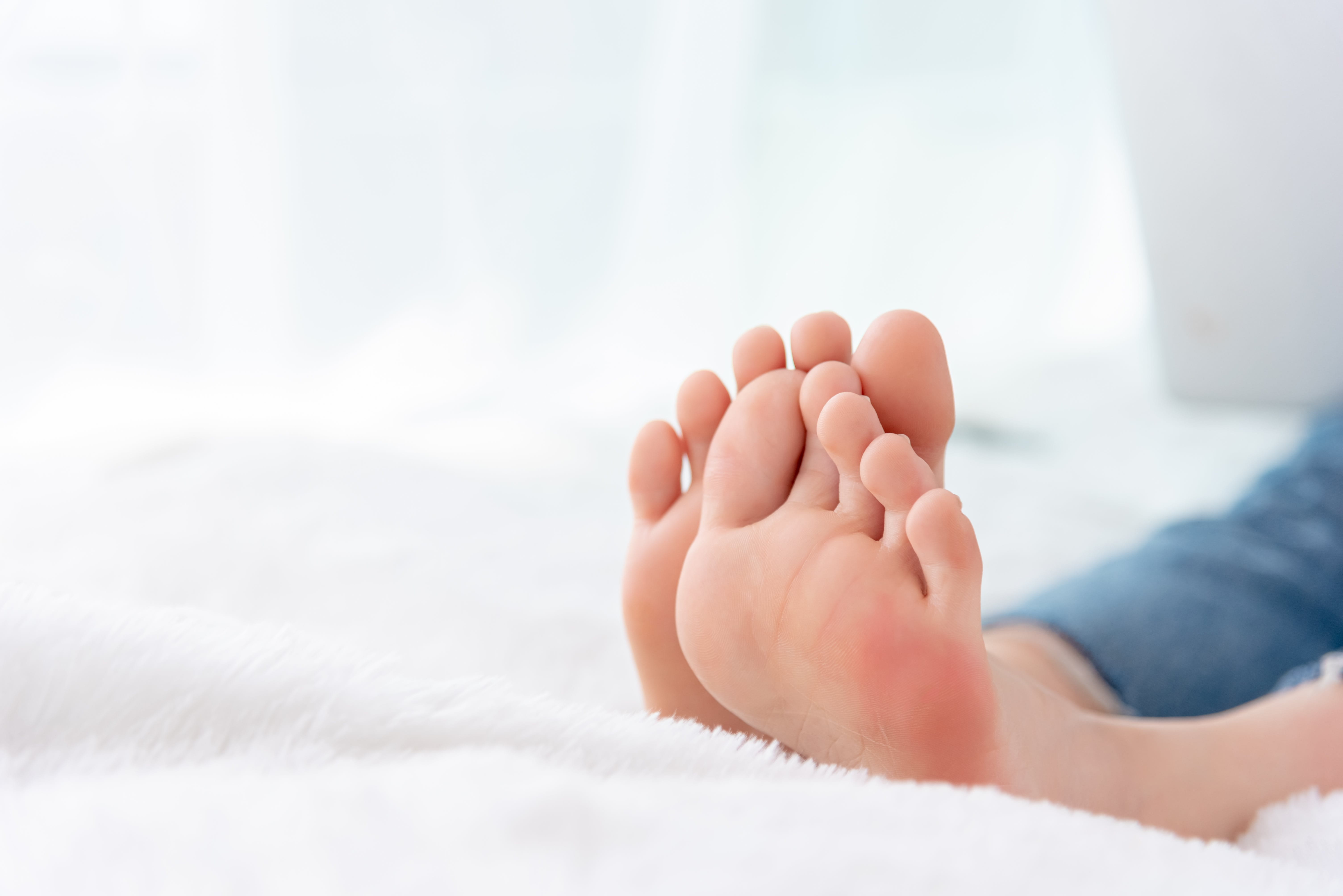 Gepflegte Füße auf einer weißen, weichen Decke.
