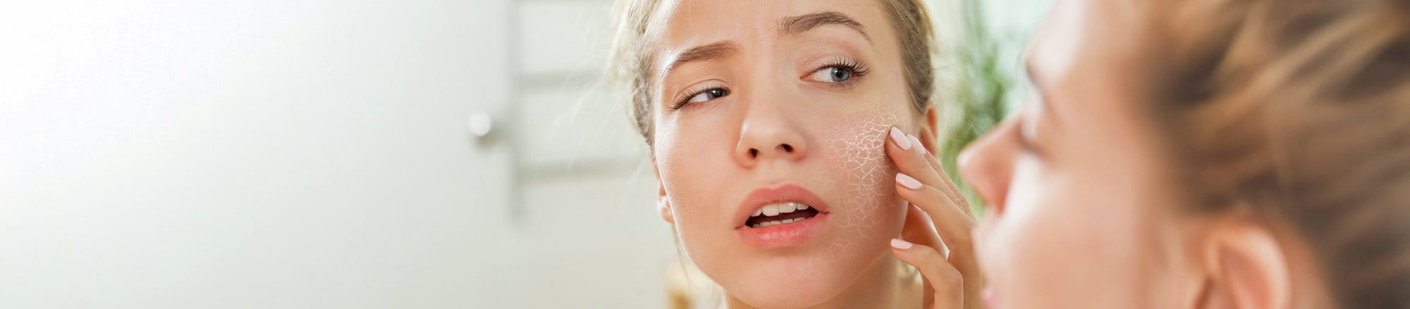 Ragazza osserva la pelle secca e screpolata allo specchio