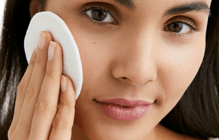 Woman with clogged pores cleans her skin with cotton pad