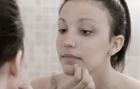 Woman touching her chin looking into a mirror
