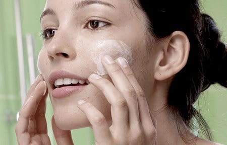 Teenager applying cream on her face.