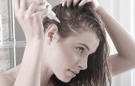 Woman applying product on scalp.