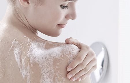 Frau pflegt Haut unter der Dusche