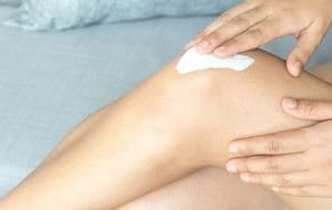 Woman applying moisturizer to her knee