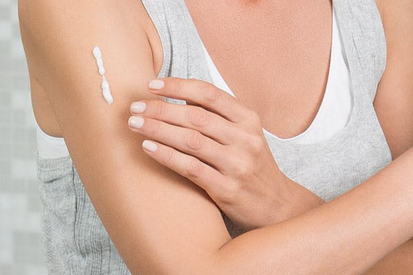 Woman applying moisturizer to her arm