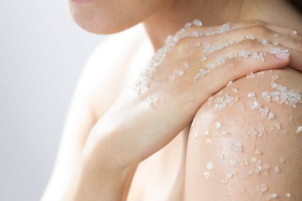 Woman applying peeling in the shower