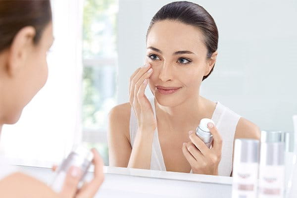 Woman applying face cream in a mirror