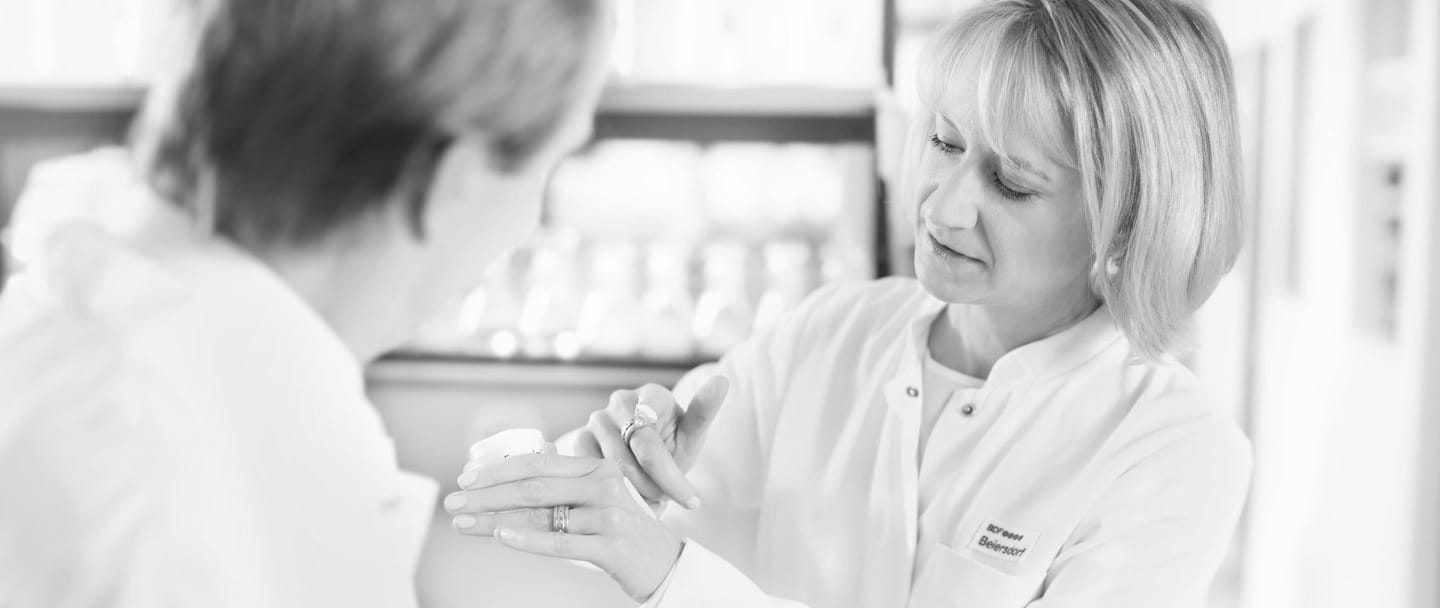 Female scientist is applying cream on the back of her hand - male scientist is watching.