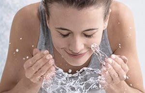 Una mujer se lava el rostro