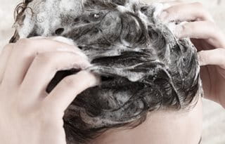 Femme qui se lave les cheveux avant d’appliquer le Soin Calmant pour le cuir chevelu