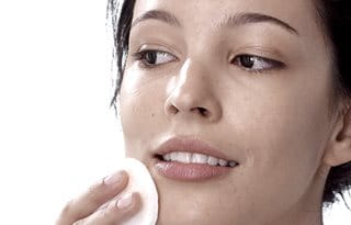 Women toning facial skin with cotton pad