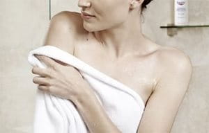 Mujer dándose toquecitos con la toalla para secarse después de la ducha